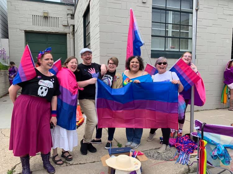 Bi+ Pride Milwaukee members hold a bi pride flag alongside JoCasta Zamarripa
